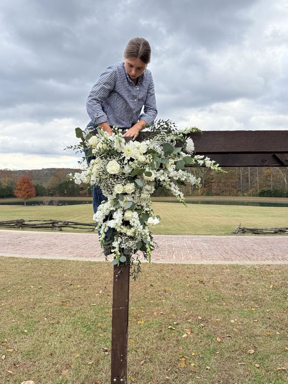 Ria building a white floral arrangement outdoors