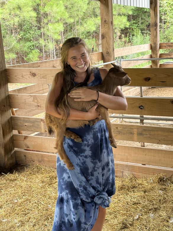 Ria holding a goat in a barn