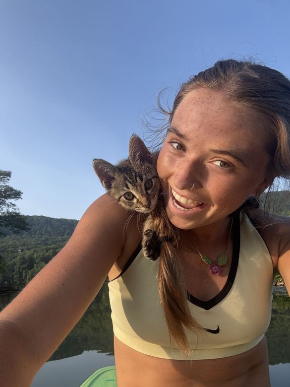 Ria smiling with a kitten on her shoulder